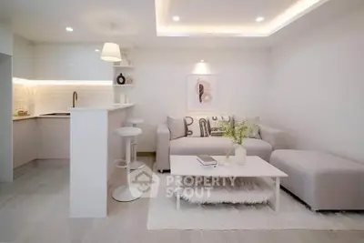 Modern living room with open kitchen, stylish decor, and cozy seating area in a bright apartment.
