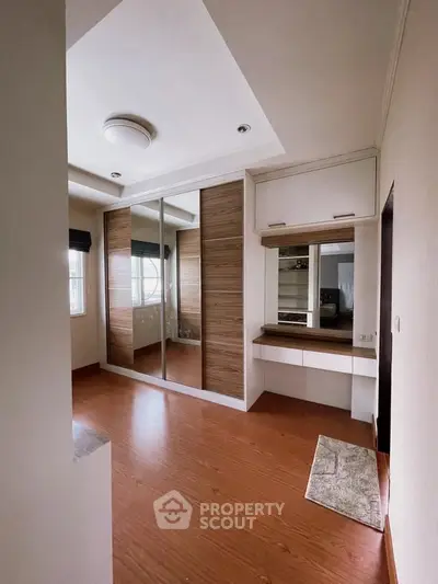Spacious bedroom with wooden flooring and built-in wardrobe, perfect for modern living.