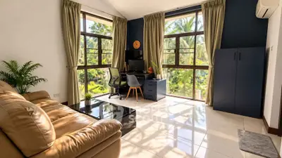 Spacious living room with large windows and garden view, featuring modern furniture and natural light.