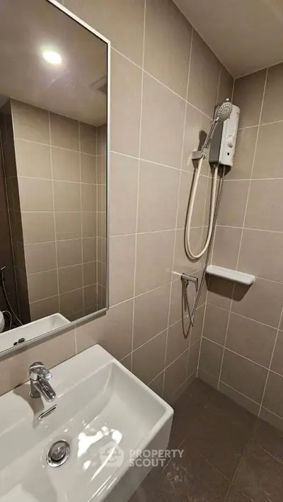 Modern bathroom with sleek tiles and a wall-mounted shower unit.