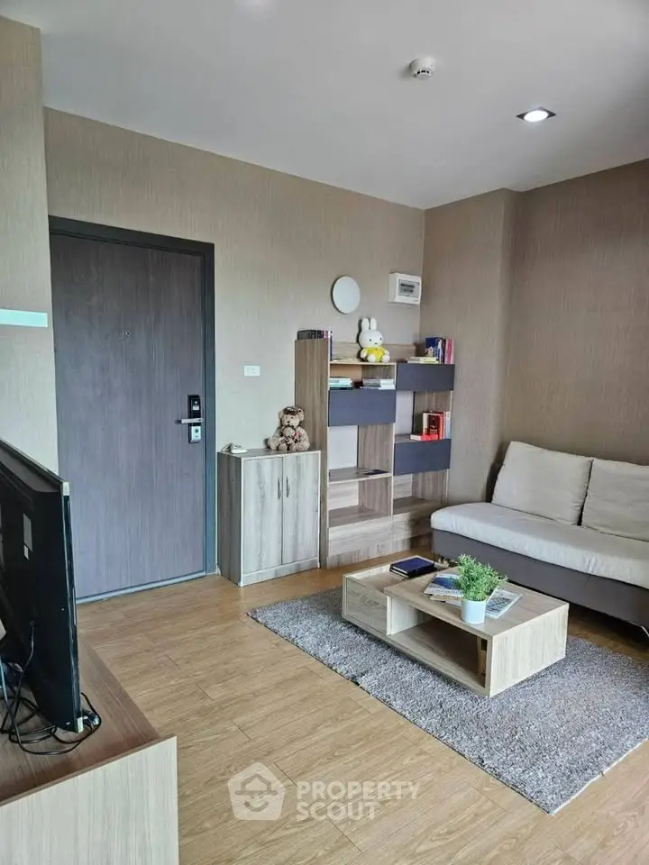 Modern living room with cozy sofa, wooden flooring, and stylish shelving unit.