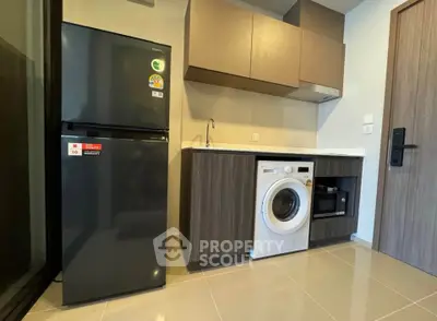 Modern kitchen with sleek appliances including fridge, washing machine, and microwave in a compact layout.