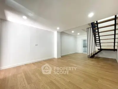 Spacious modern living room with wooden flooring and sleek staircase