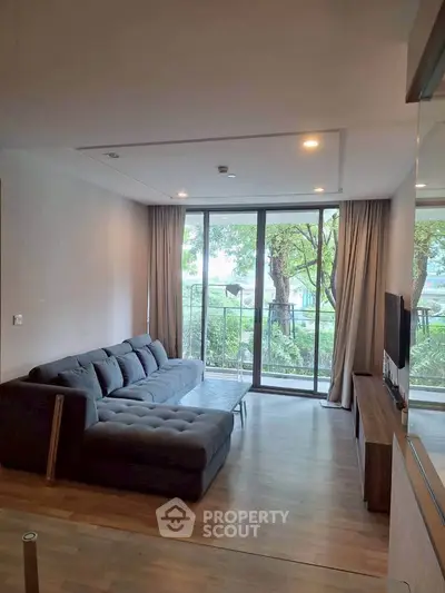 Spacious living room with large windows and garden view, featuring modern furniture and elegant decor.