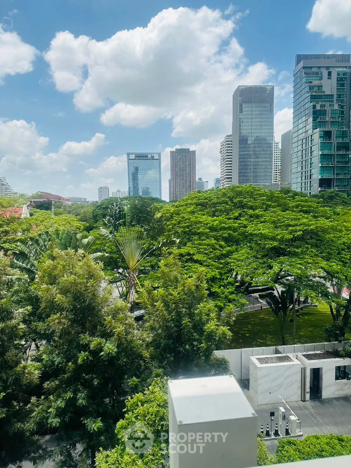Stunning urban view with lush greenery and modern skyscrapers under a bright blue sky.