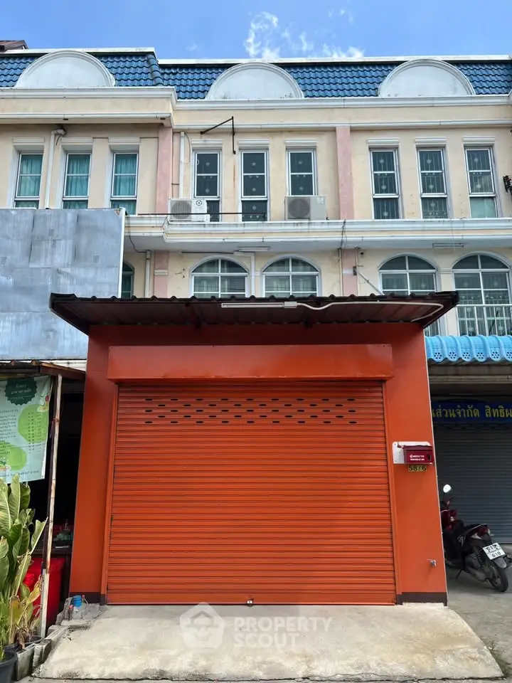 Charming townhouse with vibrant orange facade and secure garage door, ideal for urban living.