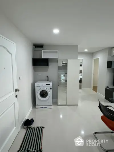 Modern apartment interior with washing machine and sleek storage solutions.