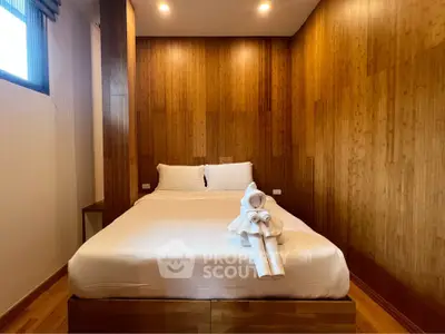 Cozy bedroom with wooden paneling and elegant bedding, perfect for relaxation and comfort.