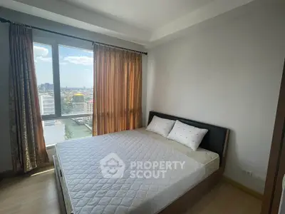 Spacious bedroom with large window offering stunning city views, perfect for urban living.