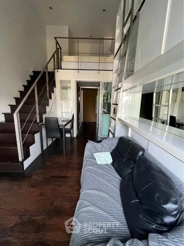 Modern loft-style living room with mezzanine and sleek staircase