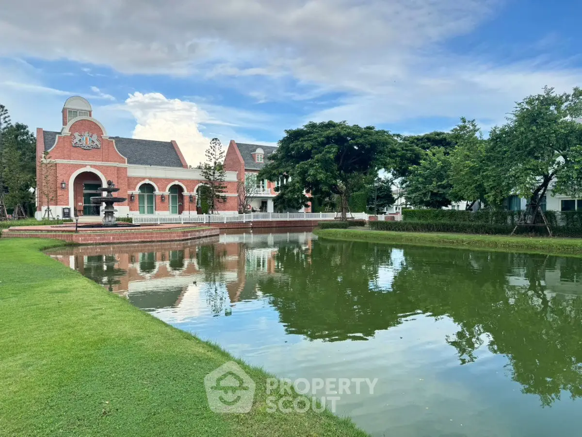 Charming brick building with serene pond and lush greenery, perfect for tranquil living.