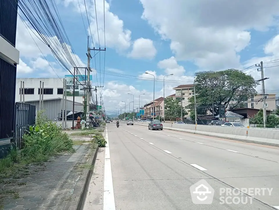 Spacious urban street view with residential buildings and clear skies, ideal for city living.