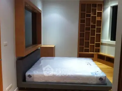 Modern bedroom with built-in wooden shelves and a new mattress in a stylish apartment.