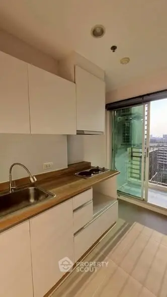 Modern kitchen with sleek cabinetry and balcony view in urban apartment
