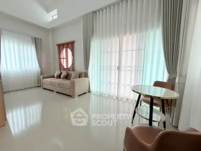 Spacious living room with elegant curtains and modern furniture, featuring a cozy sofa and stylish dining area.