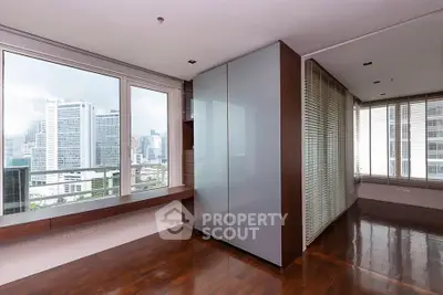 Spacious modern apartment with large windows offering stunning city views and sleek wooden flooring.