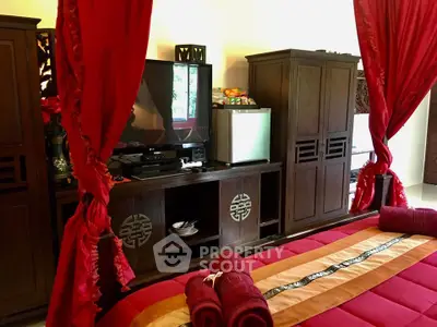 Luxurious bedroom with elegant red drapes and modern entertainment setup.