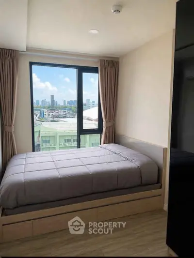 Cozy bedroom with city view, featuring a large window and modern decor.