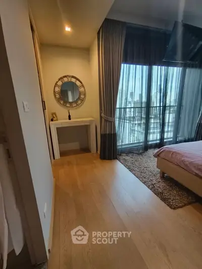 Elegant bedroom with city view, featuring a stylish mirror and floor-to-ceiling windows for natural light.