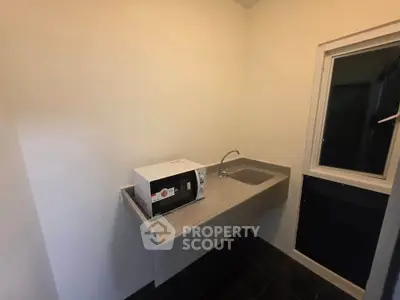 Compact kitchen area with microwave and sink, ideal for efficient cooking in small spaces.