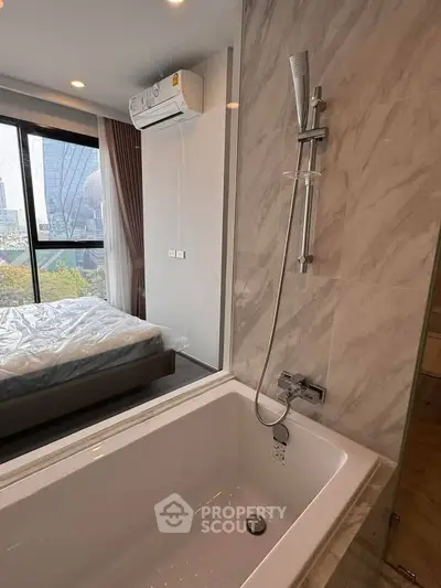 Luxurious bedroom with ensuite bathroom featuring a modern bathtub and city view.