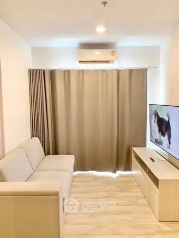 Modern living room with cozy sofa, air conditioning, and flat-screen TV, perfect for relaxation.