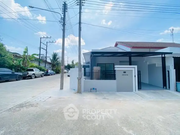 Modern single-story house with carport in a suburban neighborhood, featuring a clean driveway and clear blue sky.