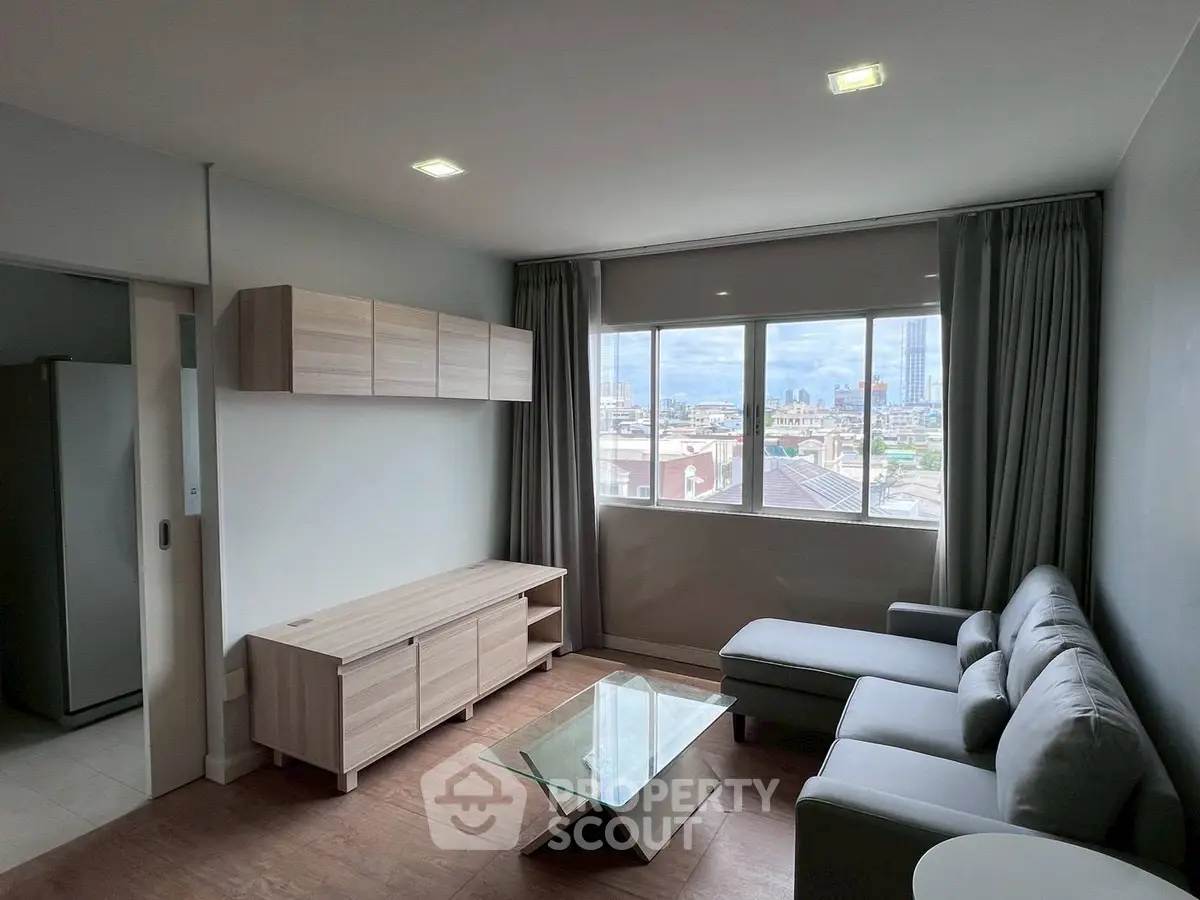 Modern living room with city view, featuring sleek furniture and large windows for natural light.