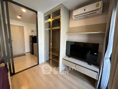 Modern living room with sleek TV setup and glass cabinet, featuring air conditioning and stylish decor.
