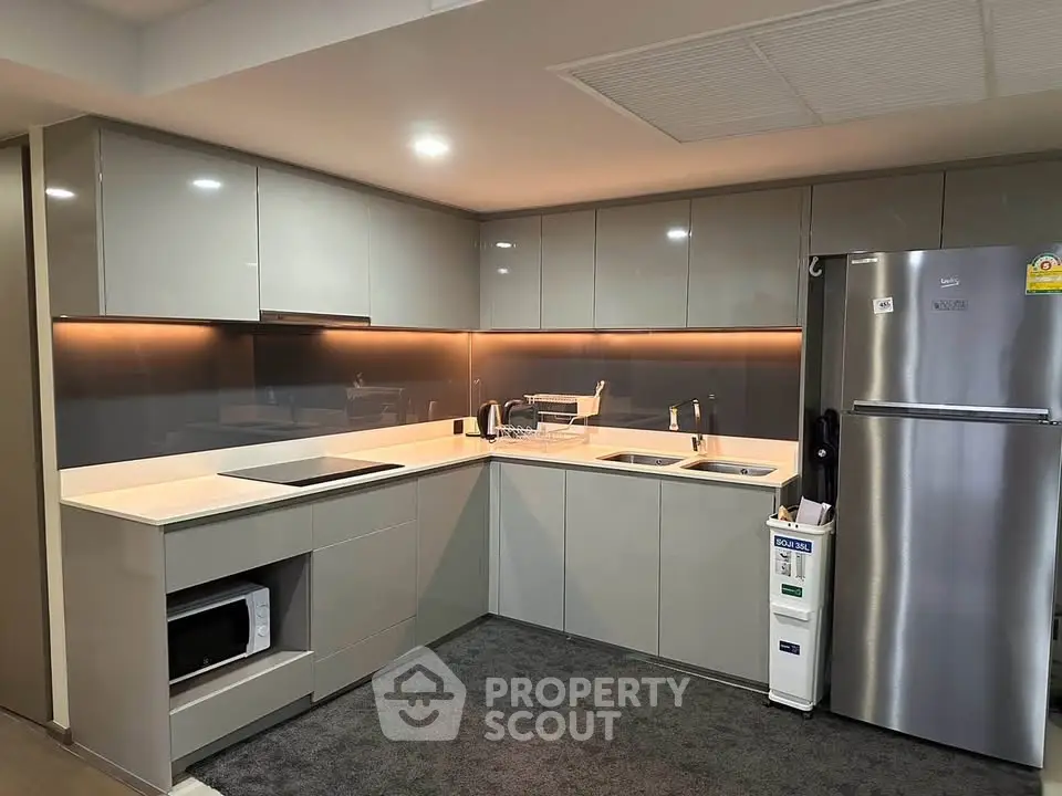 Modern kitchen with sleek cabinets, stainless steel fridge, and built-in microwave in a stylish apartment.