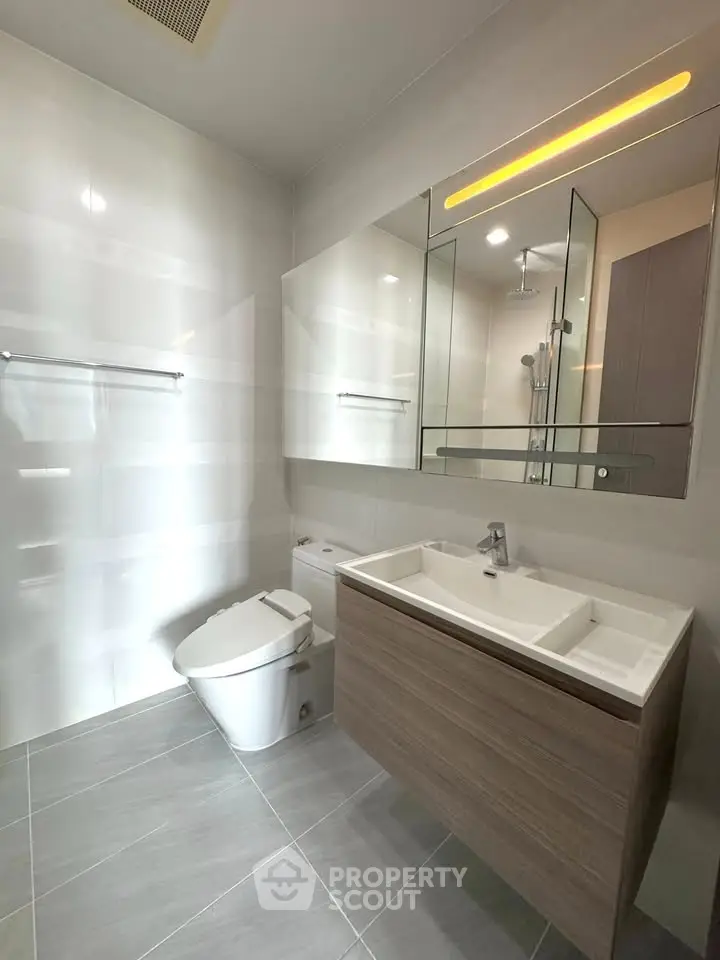 Modern bathroom with sleek fixtures and large mirror in a bright, minimalist design.