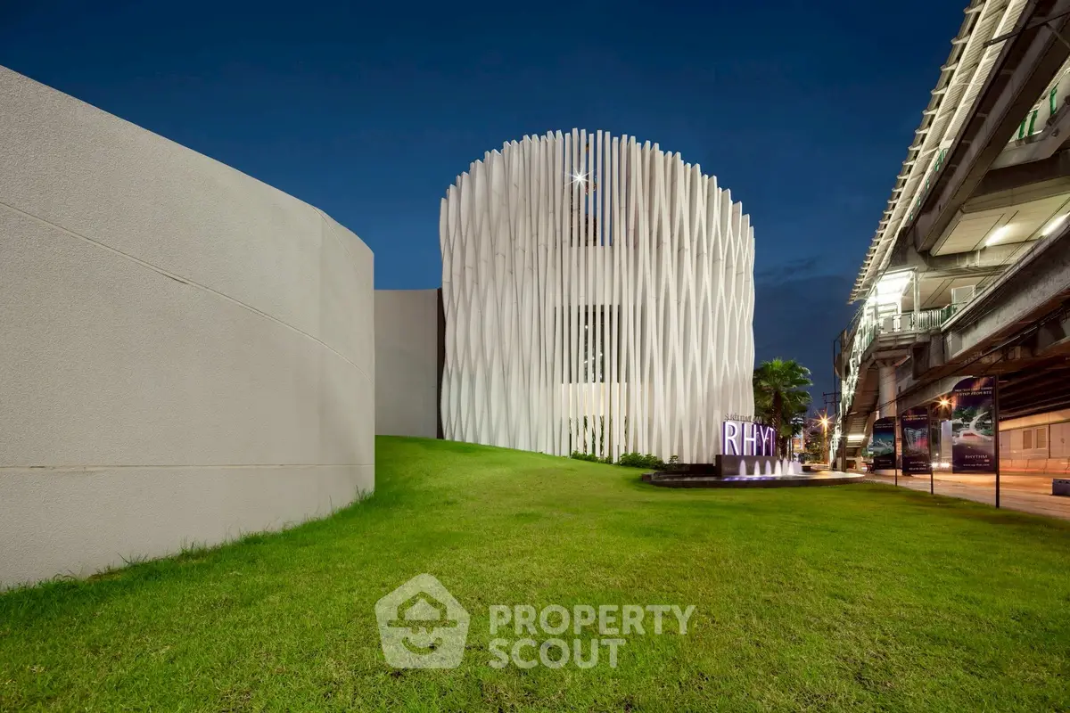 Modern architectural building with unique facade and lush green lawn at night.