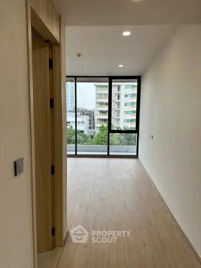 Spacious modern apartment with large windows and wooden flooring offering city views.