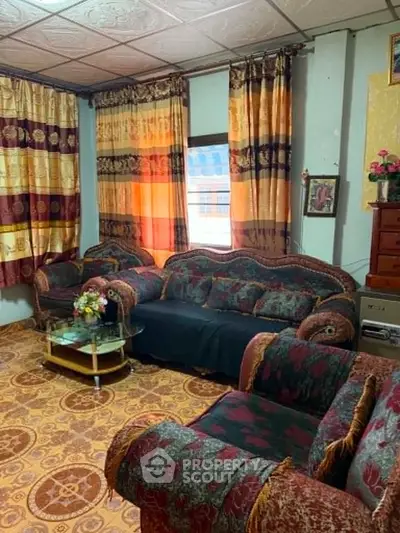 Cozy living room with patterned furniture and vibrant curtains, creating a warm and inviting atmosphere.