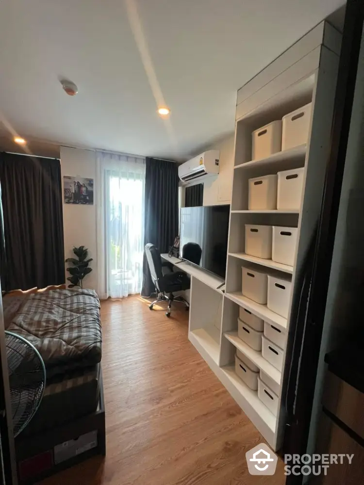 Modern bedroom with workspace, featuring sleek desk, chair, and organized shelving in cozy apartment.