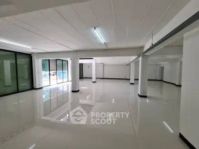 Spacious open-plan commercial space with glossy floors and large windows.