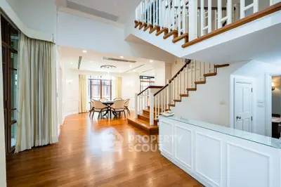 Elegant open-plan living area with wooden floors and staircase, perfect for modern family living.