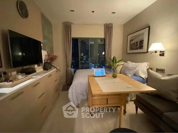 Cozy studio apartment with modern decor and city view, featuring a compact living area and stylish furnishings.