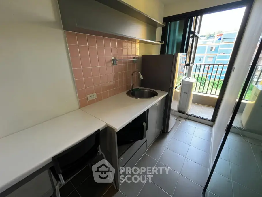 Modern compact kitchen with balcony view in urban apartment