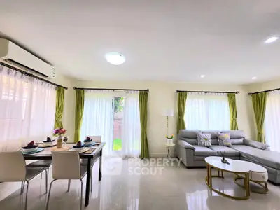 Spacious living room with modern decor and dining area, featuring large windows and elegant curtains.