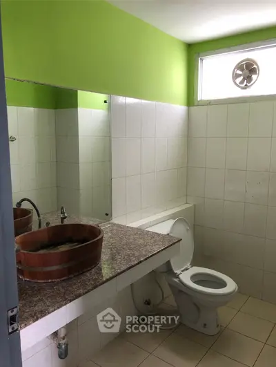 Modern bathroom with unique wooden sink and green accent wall