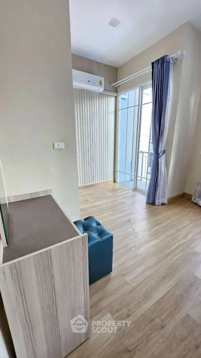 Modern living room with wooden flooring and large window balcony access