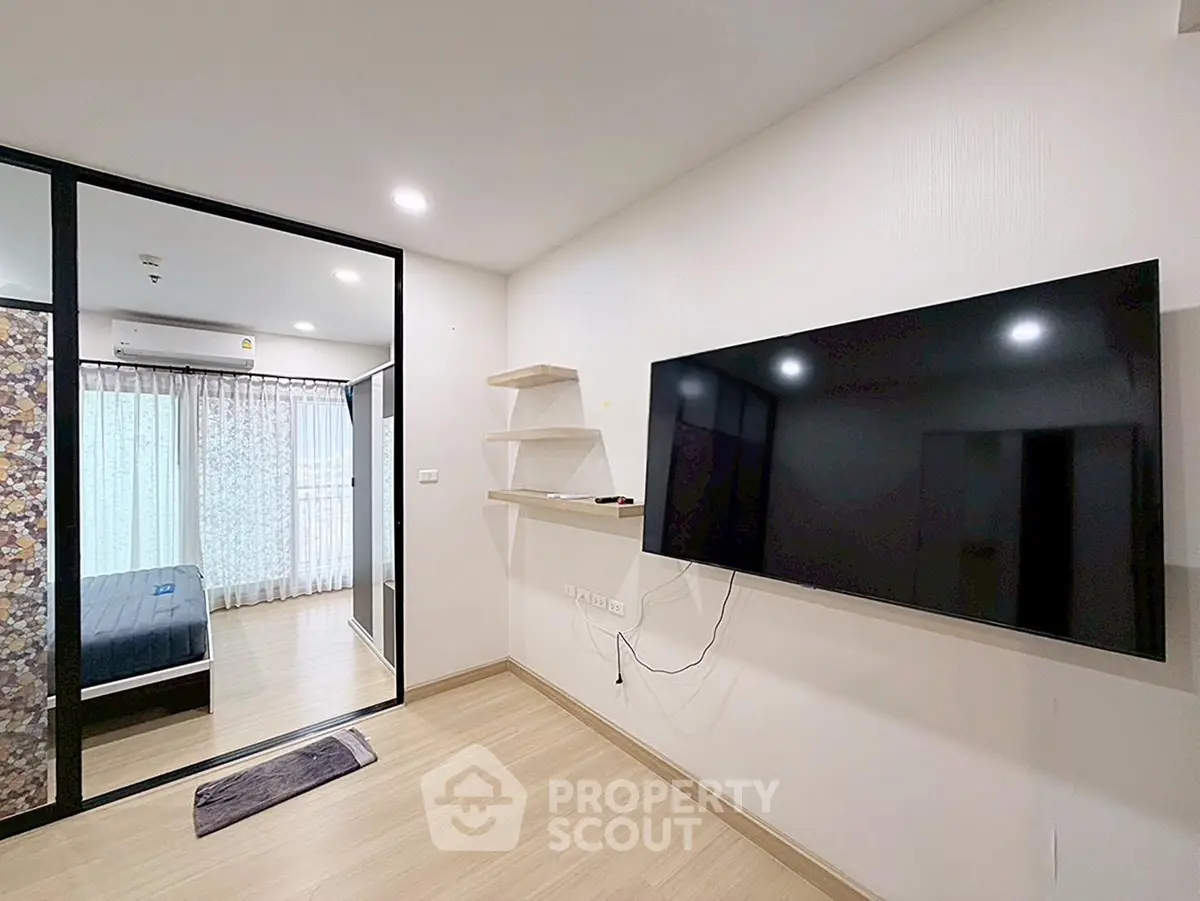 Modern living room with wall-mounted TV and view into a stylish bedroom
