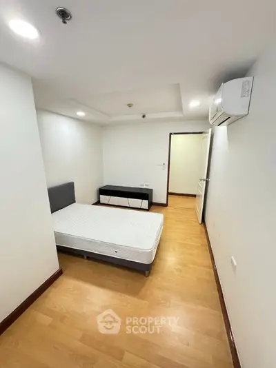 Cozy minimalist bedroom with wooden flooring and air conditioning unit