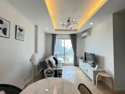 Modern living room with city view, stylish ceiling lights, and cozy furnishings.