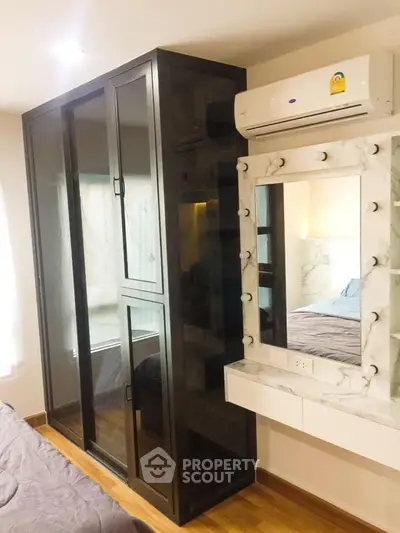 Modern bedroom with sleek black wardrobe and stylish vanity mirror with lights.