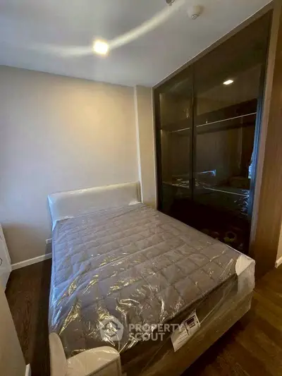 Cozy bedroom with sleek dark wardrobe and comfortable bed in modern apartment.