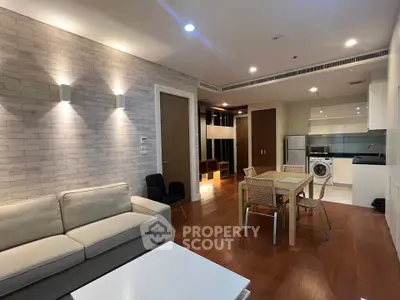 Modern open-plan living room with kitchen, featuring sleek furniture and wooden flooring.