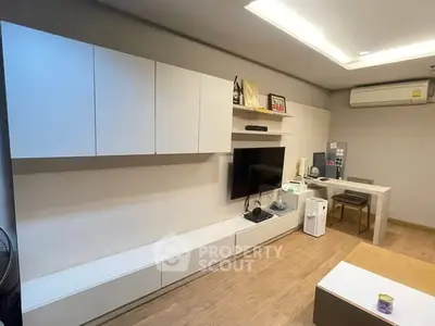 Modern living room with sleek cabinetry and wall-mounted TV, featuring minimalist design and cozy ambiance.