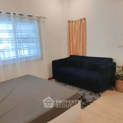 Cozy bedroom with blue sofa and large window, perfect for relaxation.